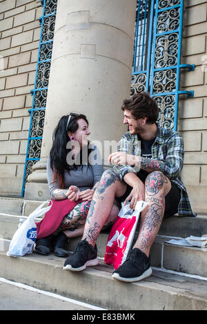 Un jeune couple avec des tatouages s'asseoir sur les marches à l'Hôtel de ville du centre-ville de Sheffield, UK Banque D'Images