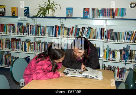 Dans la bibliothèque de Pond Inlet deux jeunes filles Inuit étudient un livre d'images Banque D'Images