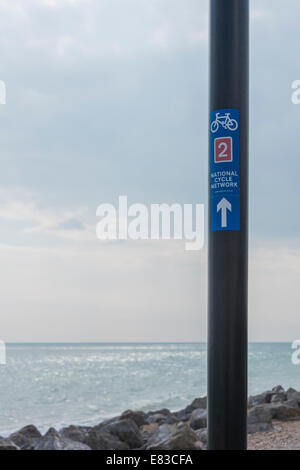 La randonnée à vélo direction signe sur un lampadaire par la mer Banque D'Images