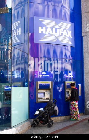 Une femme avec un enfant dans une poussette à l'aide d'un distributeur de billets ATM Halifax à Sheffield Banque D'Images