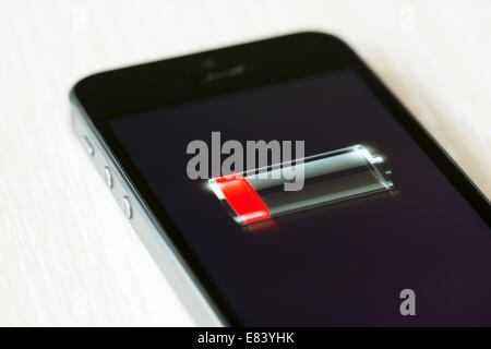 Le tout nouveau Apple iPhone 5S couchée sur un bureau avec le symbole de batterie faible sur un écran Banque D'Images