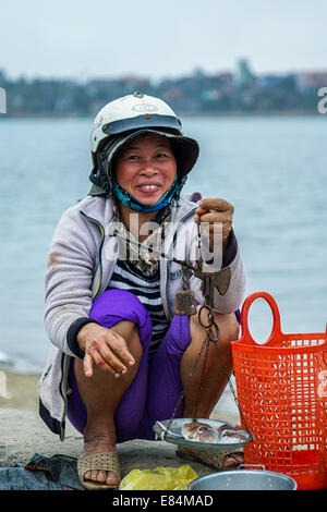 Vente de poisson à l'échelle simple femme au marché. Banque D'Images