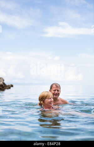 Senior couple profitant de la retraite sur un mi-ombre, se baigne dans la mer, riant ensemble, rester actif et positif Banque D'Images