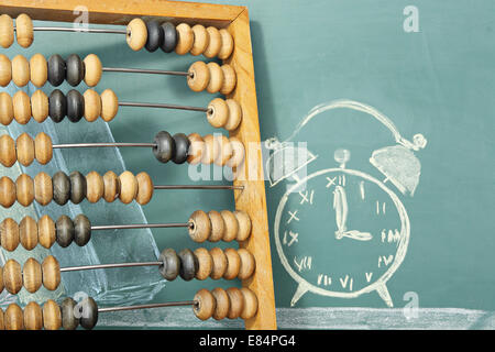 Concept de l'éducation. Abacus et dessin à la craie de réveil sur un tableau noir. Banque D'Images