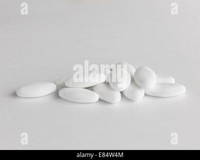 Un tas de comprimés en forme de losange blanc sur fond blanc Banque D'Images
