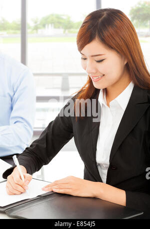 Jeune femme d'affaires écrit avec document in office Banque D'Images