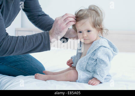 Son fixing baby girl's hair, cropped Banque D'Images