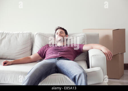 Man relaxing on sofa alors que d'un déménagement Banque D'Images