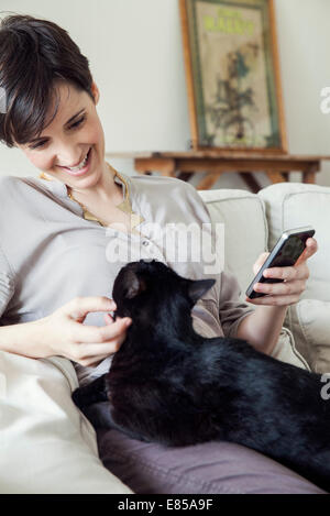 Femme assise sur le canapé avec la chatte sur ses genoux Banque D'Images