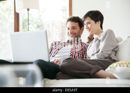 Couple relaxing together on sofa with laptop computer Banque D'Images