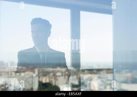 Businessman looking through window Banque D'Images