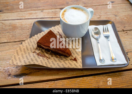 Landeau gâteau au chocolat avec du cappuccino , couteau & fourchette sur le bac Banque D'Images