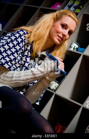 Blonde est assise sur chaise à côté de bibliothèque en robe de cavalier à motifs Banque D'Images