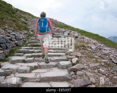 Une femme portant un sac à dos grimpe le chemin jusqu'à l'Ecosse Ben Nevis UK Banque D'Images