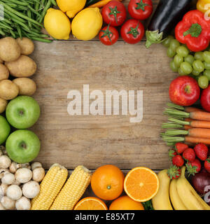 Les fruits et légumes frais formant une trame sur une planche en bois avec copyspace Banque D'Images