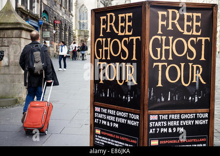 Man with suitcase walking passé Edinburgh Ghost Tour plaque-étiquette sur le Royal Mile, Edinburgh Old Town. Banque D'Images