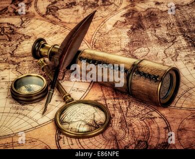 Vintage loupe, boussole, plume d'oie et spyglass allongé sur une vieille carte. Banque D'Images