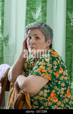 Portrait of a senior woman posant son menton sur ses mains et regarder directement l'appareil photo Banque D'Images