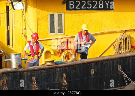 Deux ingénieurs chinois sur le pont d'un derrick péniche amarrée à Hong Kong. Banque D'Images