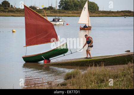 Un homme lance un canot Heybridge Roach sur la rivière Blackwater dans l'Essex. Banque D'Images