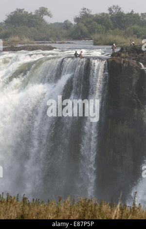 Victoria Falls au Zimbabwe. 2 octobre, 2014. Les touristes étrangers posent pour des photos avec des guides locaux à la 'Devil's pool' au-dessus des Chutes Victoria, à la frontière du Zimbabwe et de la Zambie, 30 septembre 2014. La 'Devil's pool' est un site majeur pour les touristes à des Chutes Victoria au cours de la saison sèche, en particulier pour les mois de septembre et octobre, lorsque les niveaux d'eau sont au plus bas et le cours de la rivière Zambèze est doux. Source : Xinhua/Alamy Live News Banque D'Images