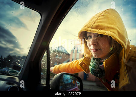 Jeune femme debout à côté d'une voiture en indiquant le sens de déplacement, Grevenbroich, Rhénanie du Nord-Westphalie, Allemagne Banque D'Images