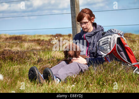 Un female hiker assis avec leur chien tandis que dehors sur une promenade dans la campagne. Banque D'Images