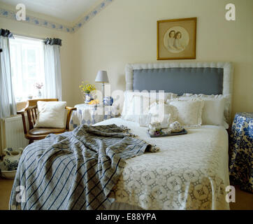 Cottage Chambre avec tête de lit rembourrée bleue sur lit avec coussins plumeuse et bleu vu jeter Banque D'Images