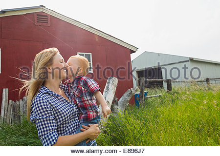 Little Boy kissing mother on joue, à l'extérieur par barn
