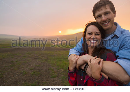 Portrait de couple hugging in field at sunset