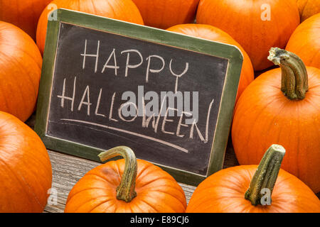 Happy Halloween - écriture à la craie blanche sur un tableau noir ardoise vintage entouré de citrouilles Banque D'Images