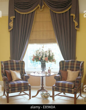Tartan bleu fauteuils de chaque côté de la fenêtre avec des rideaux bleus et crème blind Banque D'Images