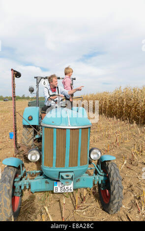 Père et fils sur le tracteur dans un champ, Bavière, Allemagne Banque D'Images