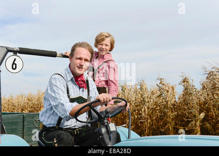 Père et fils sur le tracteur dans un champ, Bavière, Allemagne Banque D'Images