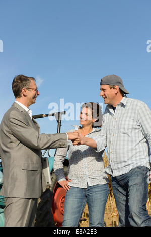 Quelques agriculteurs et businessman shaking hands in cornfield, Bavière, Allemagne Banque D'Images