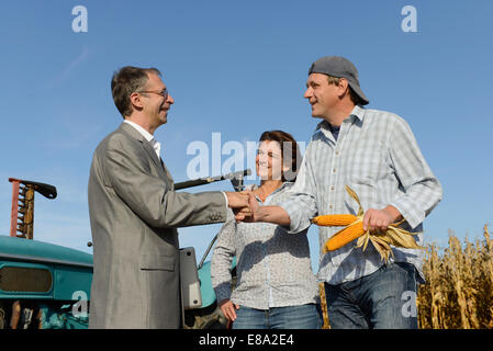 Quelques agriculteurs et businessman shaking hands in cornfield, Bavière, Allemagne Banque D'Images