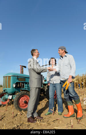 Quelques agriculteurs et businessman shaking hands in cornfield, Bavière, Allemagne Banque D'Images