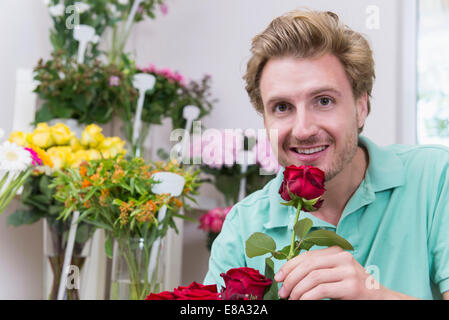 Portrait of mid adult man holding Red Rose, smiling Banque D'Images