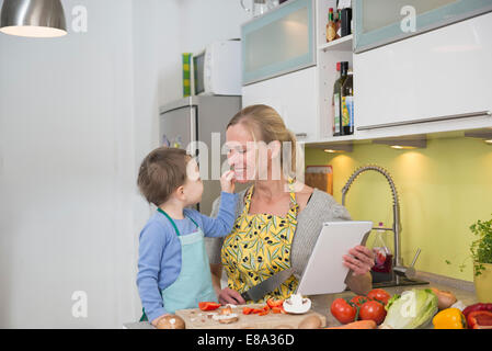 Alimentation garçon sa mère avec des légumes en tranches, smiling Banque D'Images