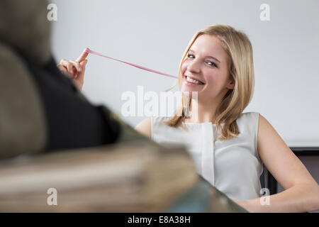 Portrait of businesswoman pulling chewing-gum, smiling Banque D'Images