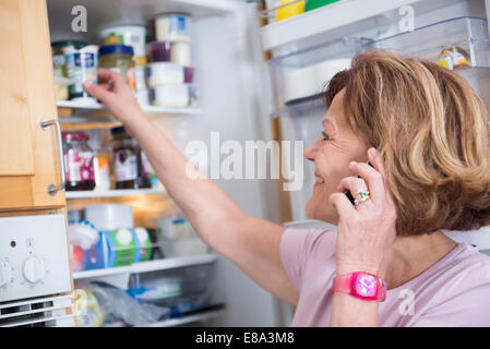 Senior woman devant ouvrir réfrigérateur, smiling Banque D'Images