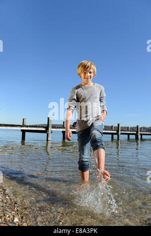 Garçon aux projections d'eau avec ses pieds, smiling, Bavière, Allemagne Banque D'Images