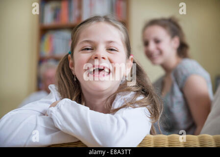 Portrait of sisters sitting on sofa in living room, smiling Banque D'Images