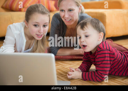 Family using laptop in living room, smiling Banque D'Images