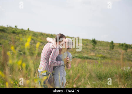 Mature couple kissing in field Banque D'Images