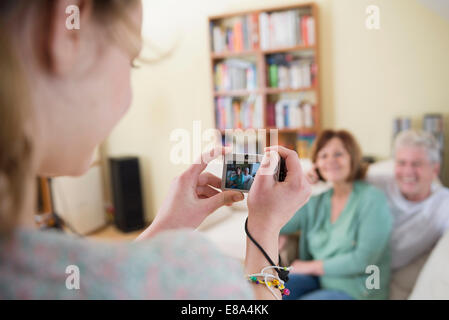 Petite-fille de prendre une photographie des grands-parents sur la table dans la salle de séjour Banque D'Images