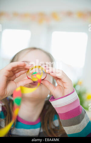 Portrait of Girl with blowout paper streamer at Birthday party, smiling Banque D'Images