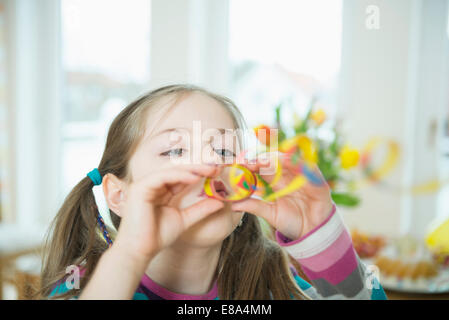 Portrait of Girl with blowout paper streamer at Birthday party, smiling Banque D'Images