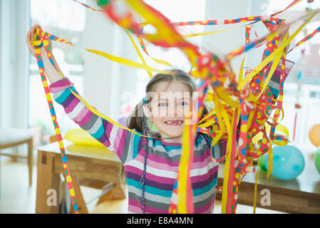 Portrait of Girl with blowout paper streamer at Birthday party, smiling Banque D'Images