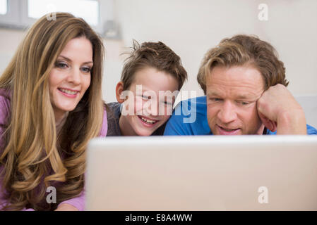 Happy Family lying on floor looking at laptop Banque D'Images